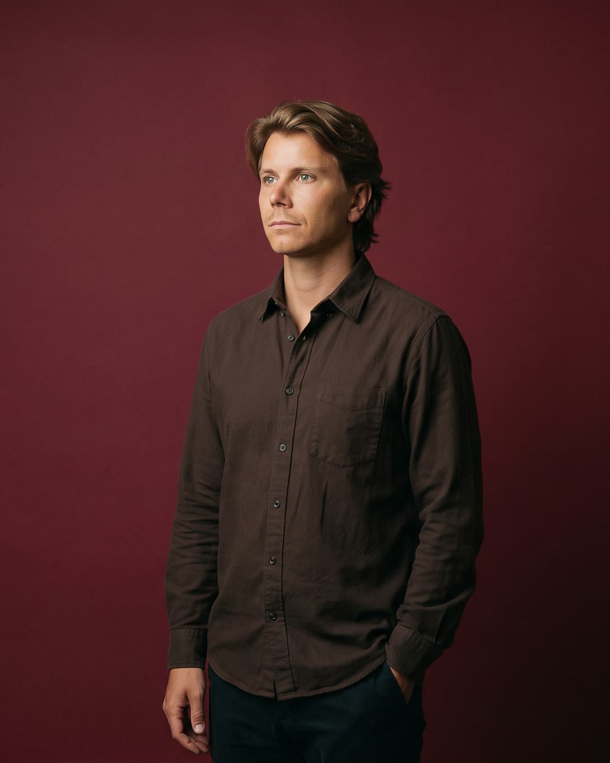 Portrait of Julius, co-founder of Plant, standing against a deep burgundy studio backdrop.